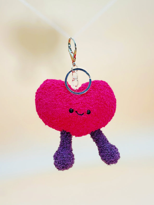 Pink heart-shaped keychain with legs on a light background