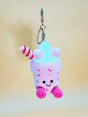 Crocheted milk shake keychain with a smiley face on a plain background
